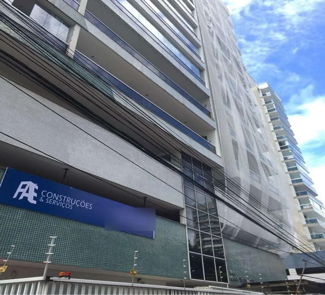 Fachada de edifício em obra de recuperação estrutural com tela de proteção e banner da Faé Construções, em Vila Velha-ES
