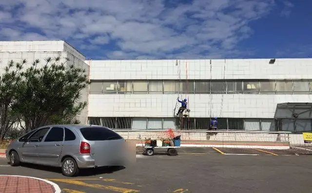 Profissional em acesso por corda executando lavagem e pintura da fachada do Vitória Apart Hospital